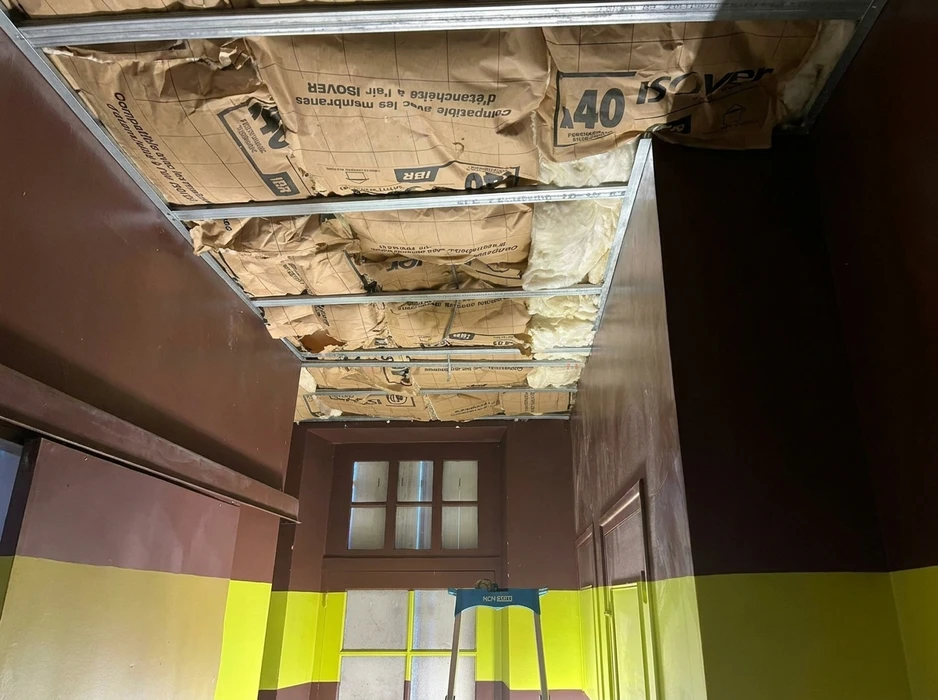 Chantier intérieur d'un couloir en rénovation, murs peints marron et jaune-vert