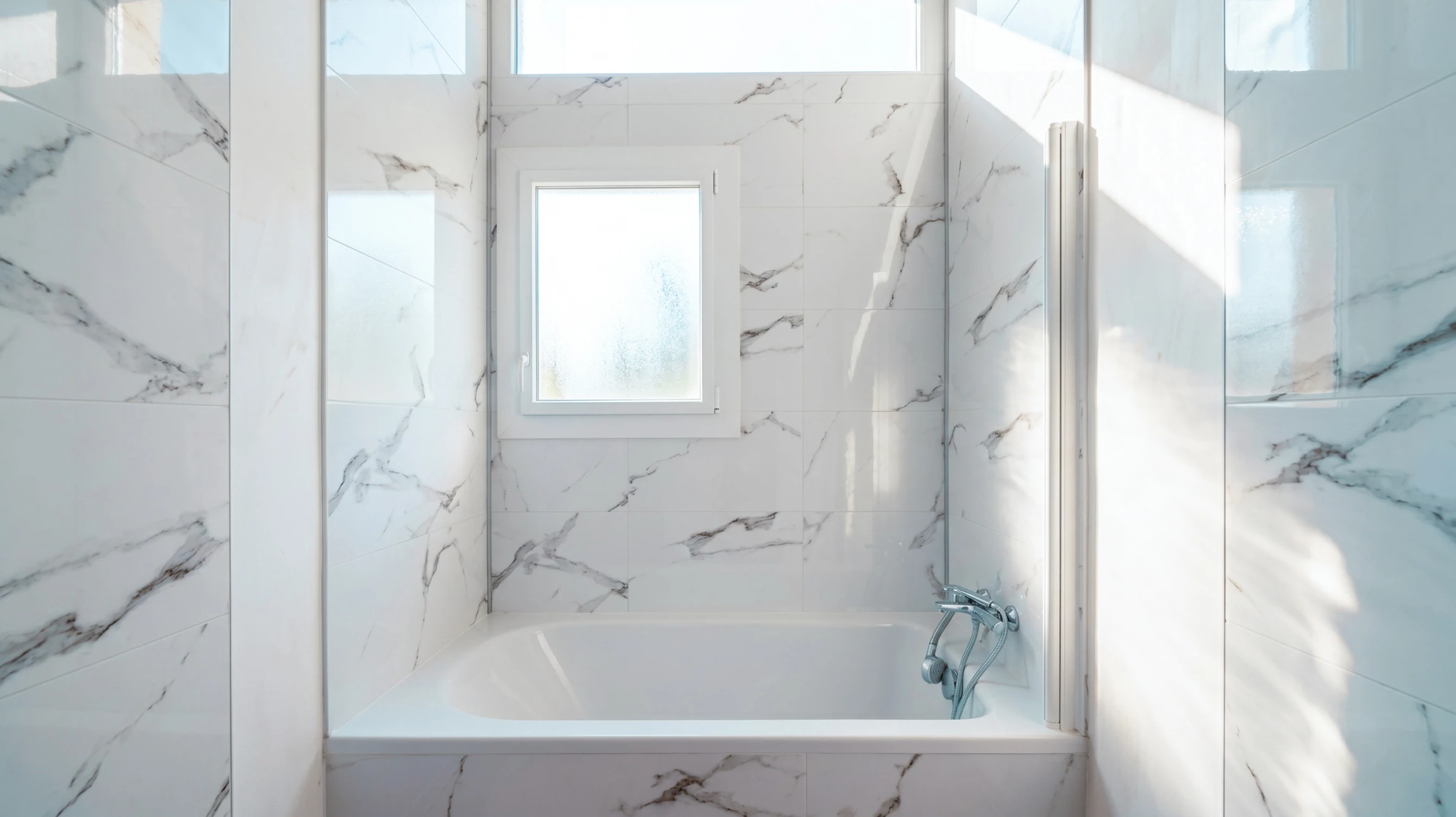 Salle de bain moderne avec toilettes suspendues blanches, baignoire encastrée rectangulaire blanche et douche à l'italienne vitrée